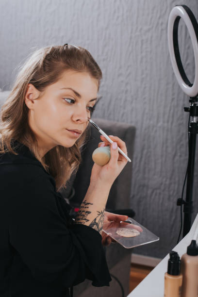 Beautiful young woman applying face powder with brush.