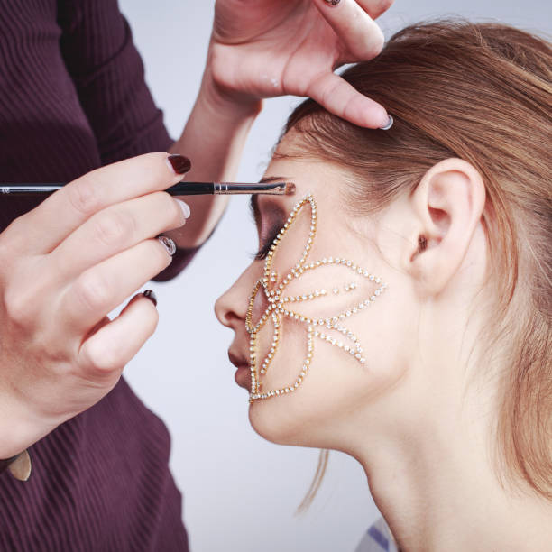 Young woman having make up applying by artist in studio